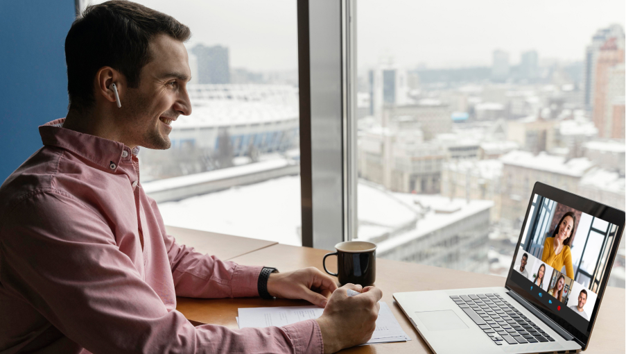 A person having an online meeting on a laptop by the window of a conference room